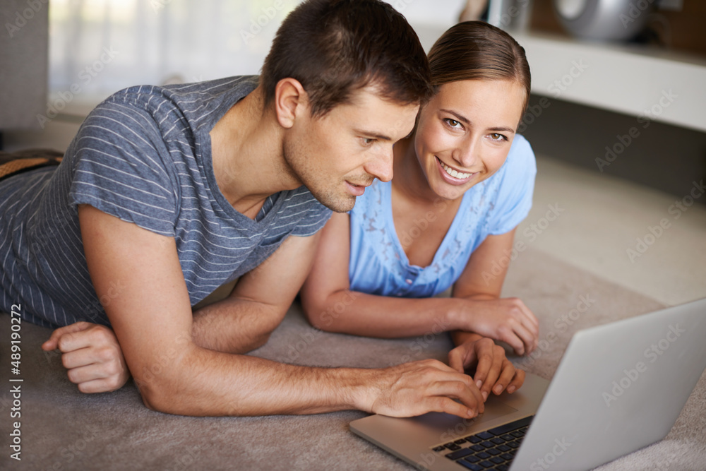 Getting all their info online. Shot of a happy young couple using a laptop on the floor together.