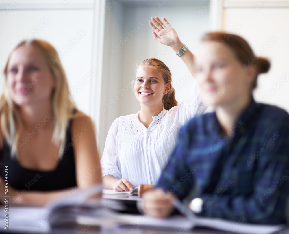 Knowledge is power. A teenage girl putting up her hand in class.