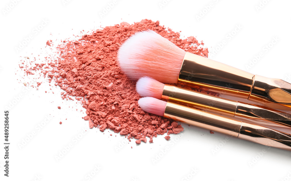 Makeup brushes and loose eye shadow on white background