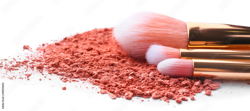 Makeup brushes and loose eye shadow on white background