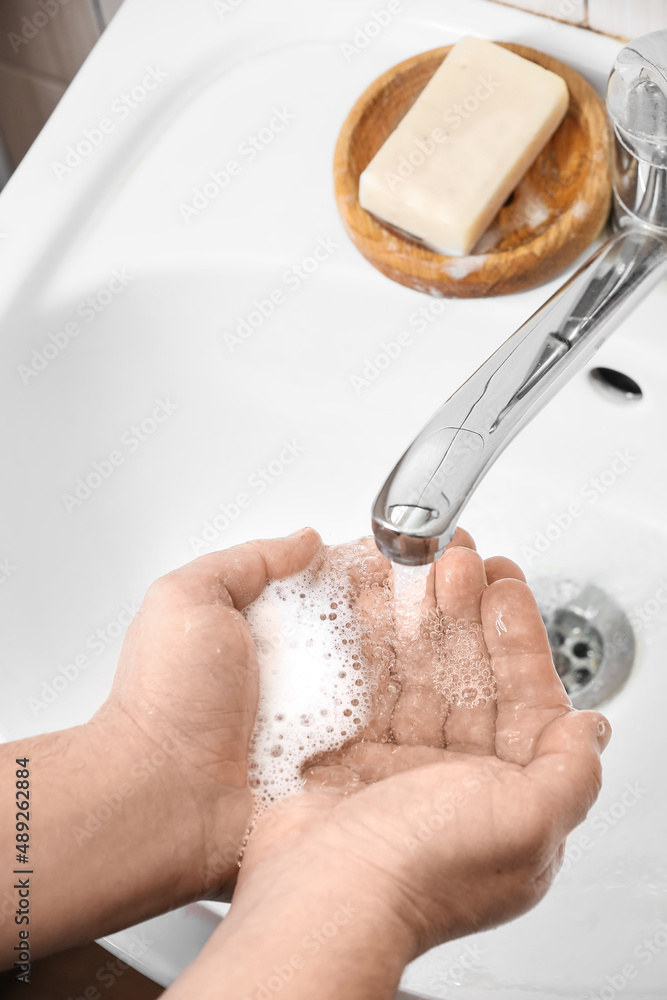 Man washing his hands with liquid soap near sink in bathroom, closeup