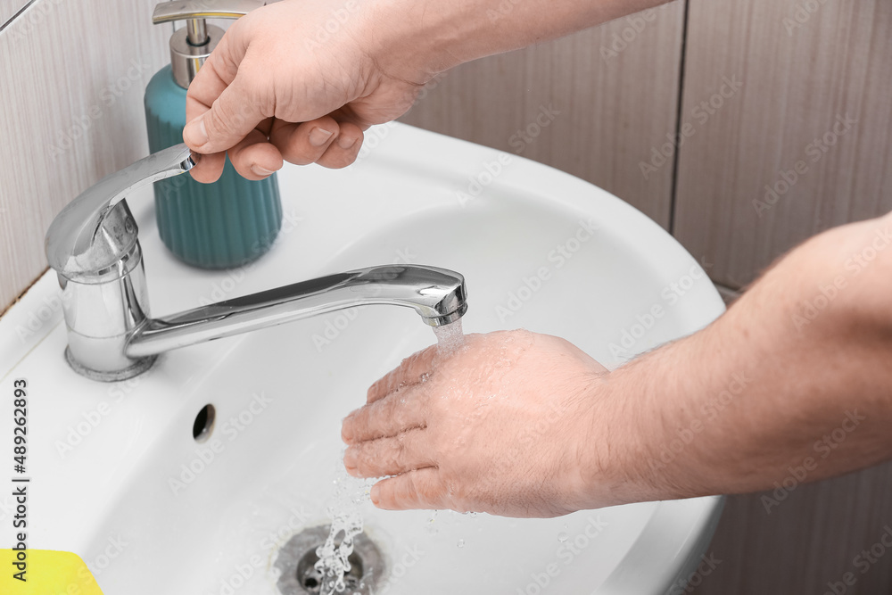 Man turning off tap in bathroom, closeup