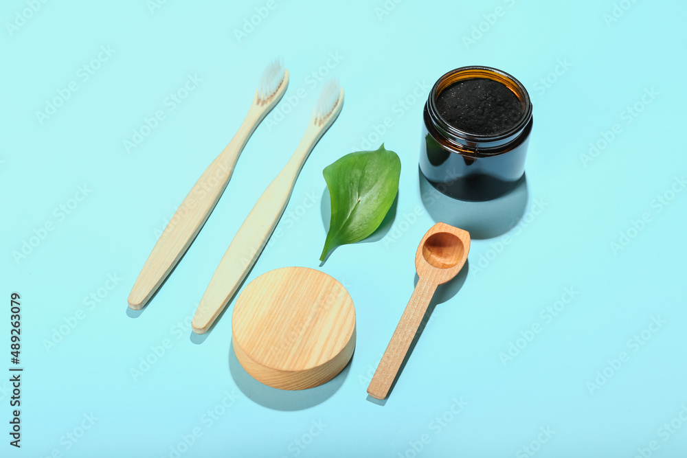 Jar with activated charcoal tooth powder and toothbrushes on blue background