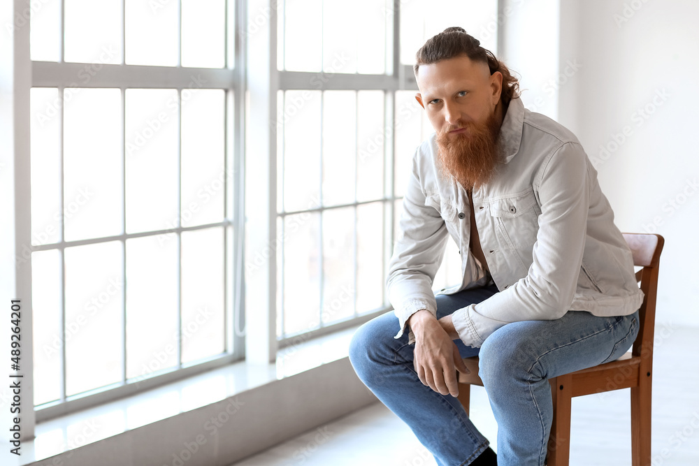 Portrait of handsome bearded man sitting on chair at home