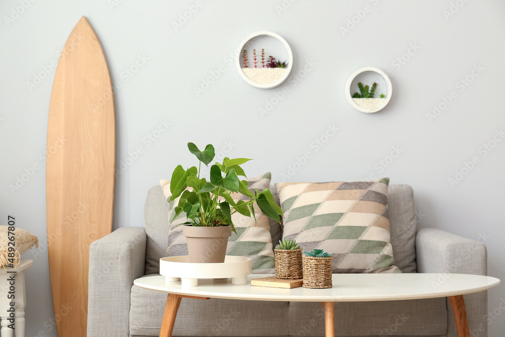 Interior of light living room with wooden surfboard, sofa and table