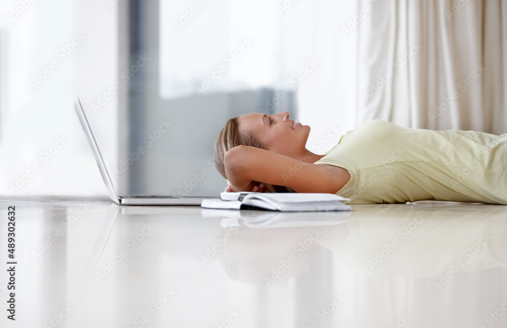 Comfortable while connected. A young woman lying on her floor at home next to her laptop and a noteb