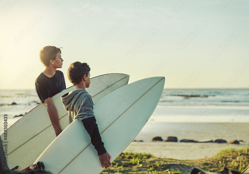 海浪在等着。两个年轻的兄弟拿着冲浪板向大海看的照片