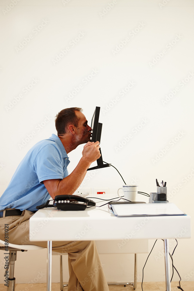 Thank you. A middle-aged man ethusiastically kissing his computer screen while sitting at his desk.