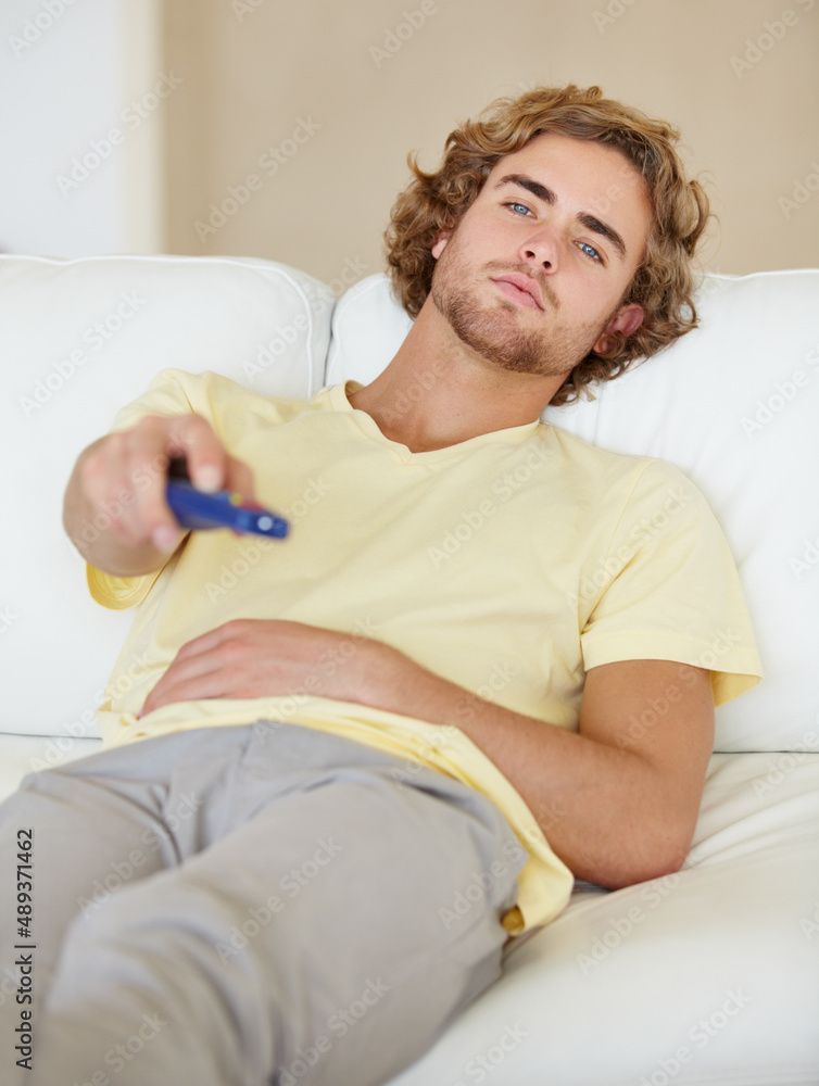 Chilling. A lazy young man flicking through TV channels.