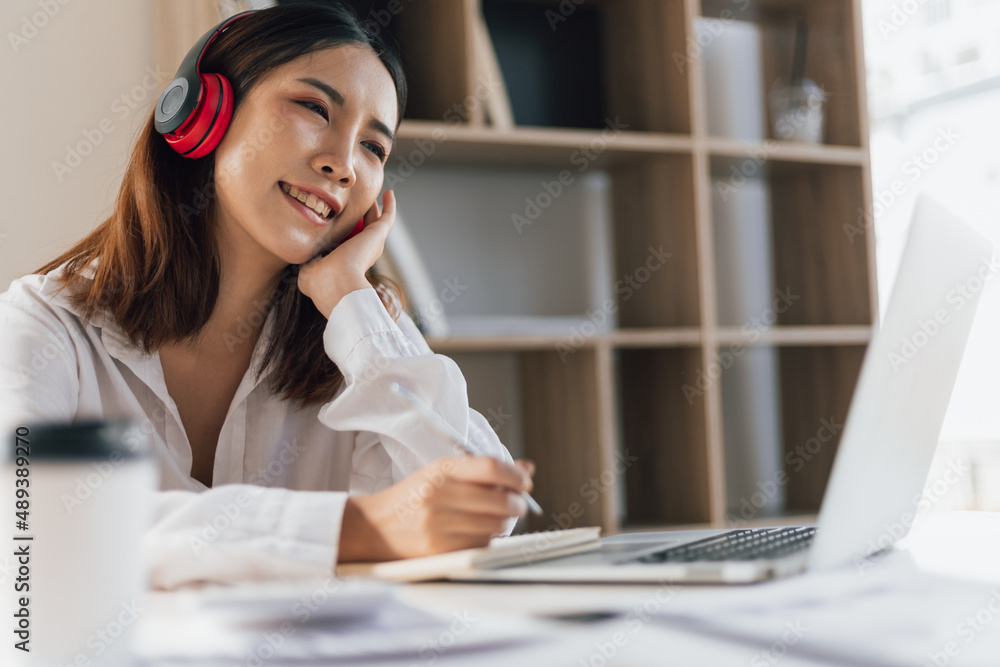 Woman wearing headphones working with laptop during online meeting. Internet work from home and onli