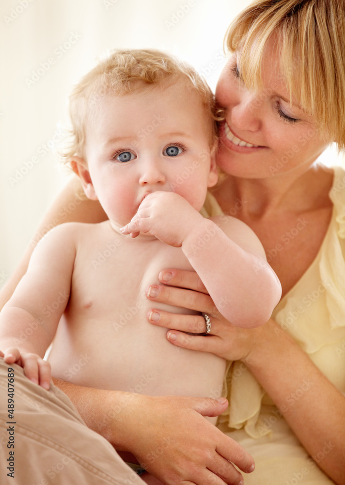 Shes proud of her little boy. Cute baby boy looking at you while being held by his smiling mother.