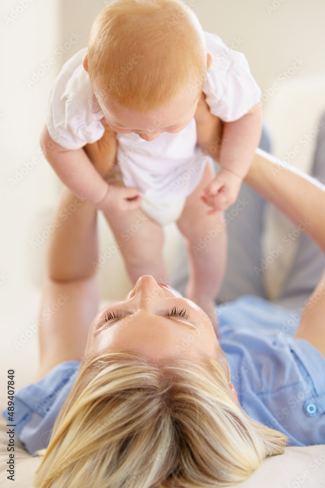 Mom and daughter bonding together. An adorable baby girl being lifted into the air by her mother.