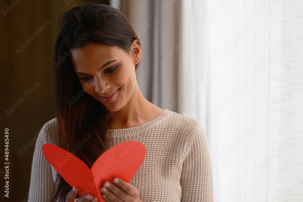 He knows just how to win me over. Shot of an attractive young woman reading a valentines day card at