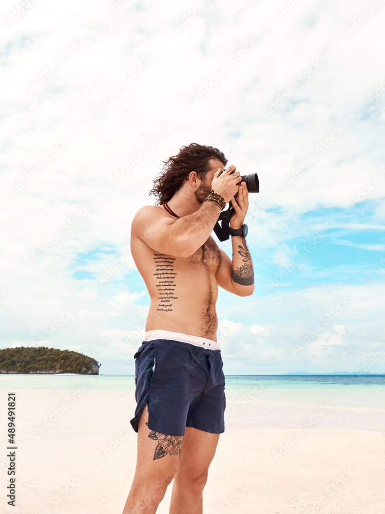 The beach is a photographers paradise. Shot of a young man taking pictures with his camera at the be