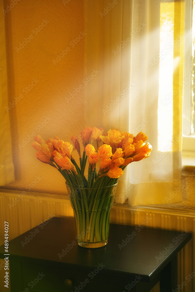 Sunlit tulips on the sidetable. Tulip arrangement standing on a sidetable in front of a window.