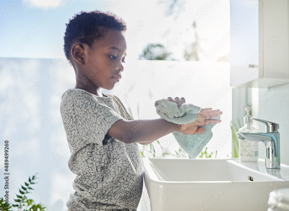 Hes a clean kid. Shot of a little boy drying his hands with a towel in a bathroom at home.