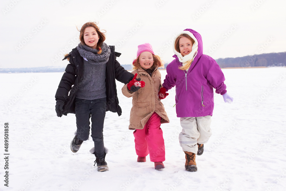 让我们去做雪天使吧。三个年轻的姐妹在外面的雪地里奔跑。