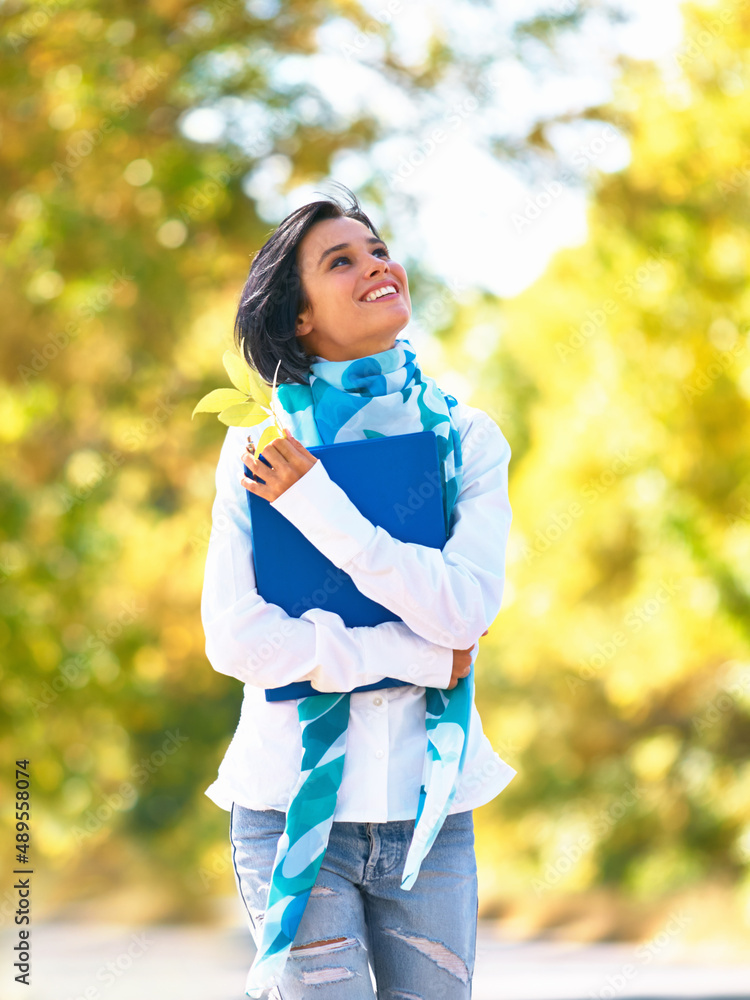 Autumn stroll. A young woman strolling down the street admiring the autumn leaves.