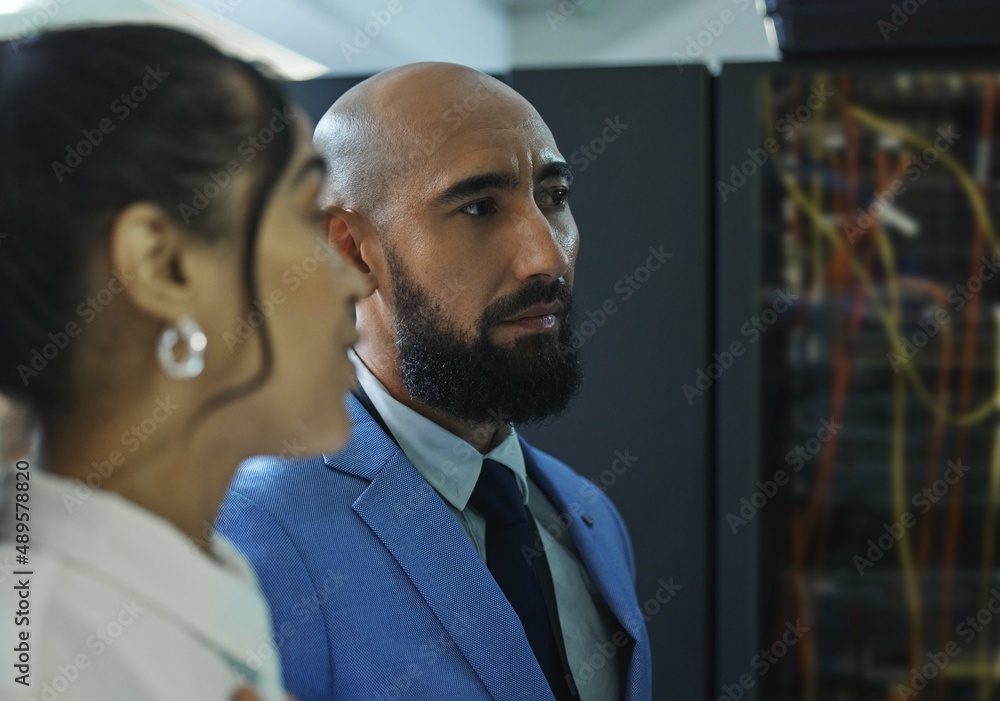 The final inspection. Shot of two young workers doing maintenance checks in a server room at work.