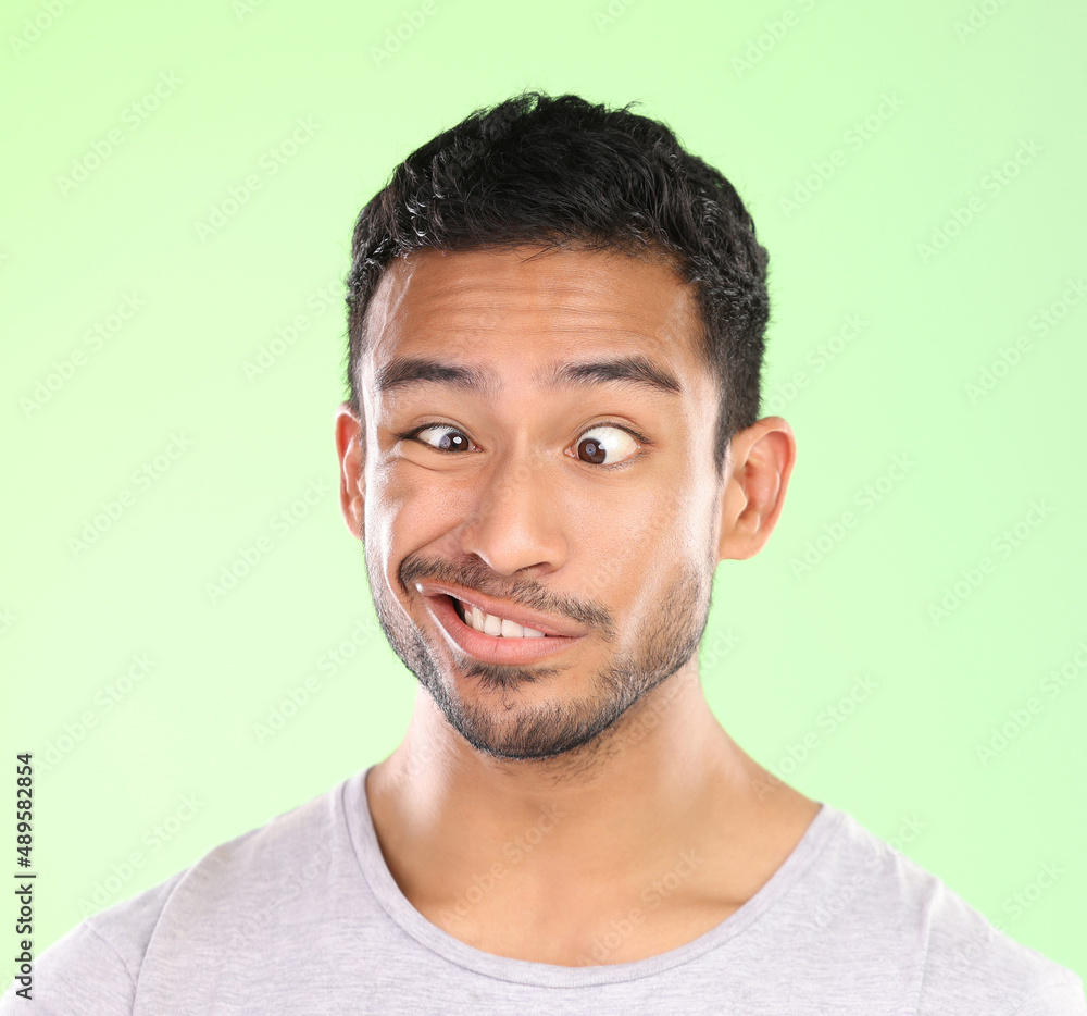 Ah duh. Cropped shot of a handsome young man making a face against a green background in studio.