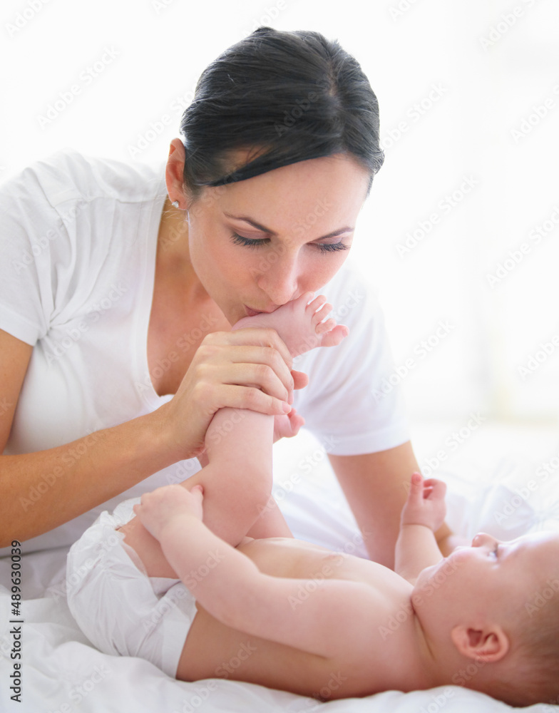 Abundant love from head to toes. Beautiful woman kissing her babys feet.