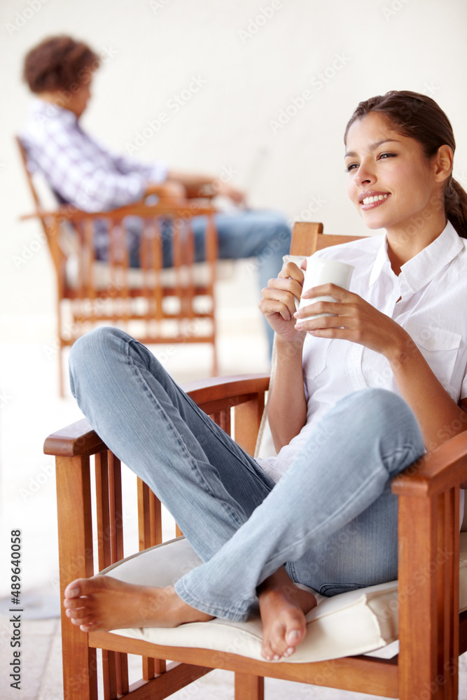 Lifes feeling balanced. Beautiful woman looking away happily with a man relaxing in the backgroun.