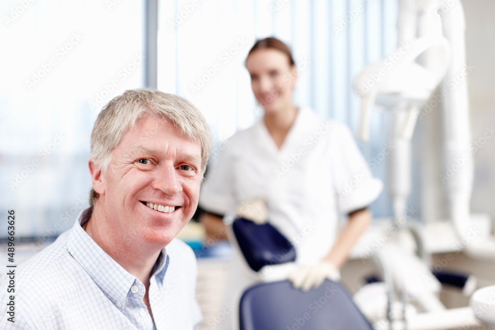 Smiling doctor with assistant. Portrait of handsome dentist smiling with his assistant in office.