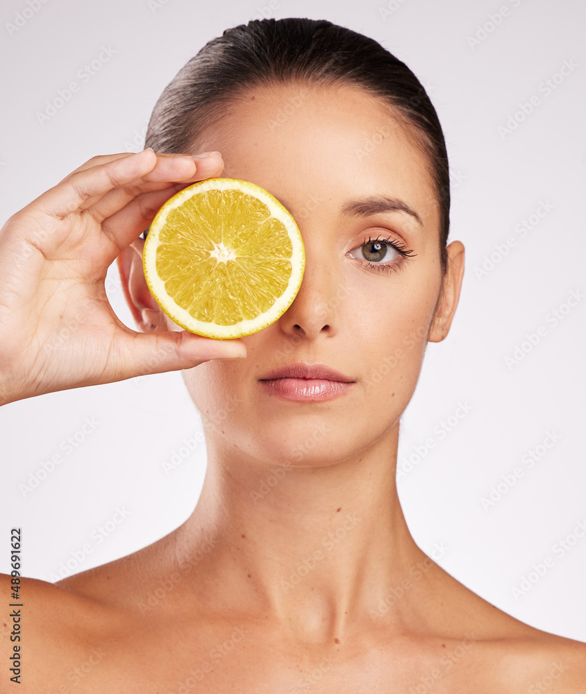 Vitamin C does it for me. Shot of an attractive young woman holding an orange against a studio backg