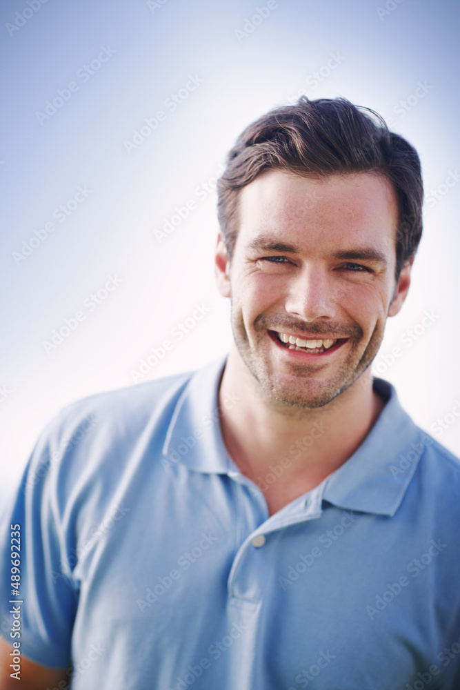 Cool and casual. Portrait of a handsome man smiling happily while standing outside.