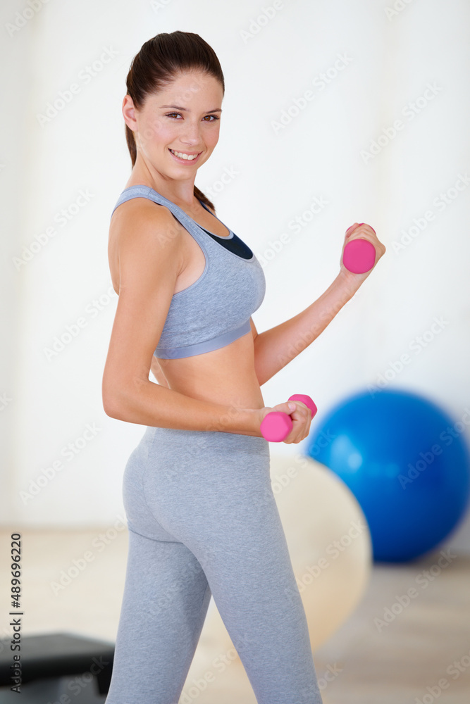 She works hard to stay fit. Portrait of a beautiful young woman fitness training with dumbbells.