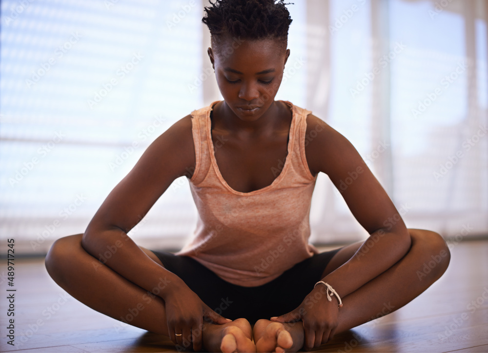 Clearing her mind and body during warm up. Shot of a young woman dancer stretching in a studio.