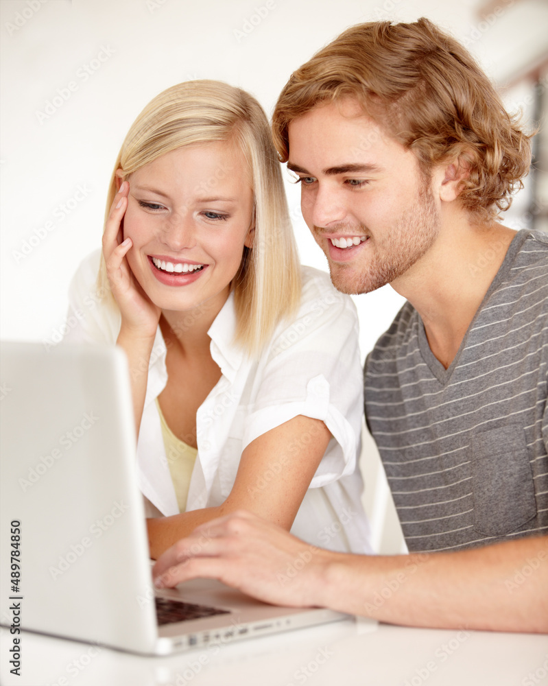 Reading his latest blog. A young couple using a laptop to surf the net.