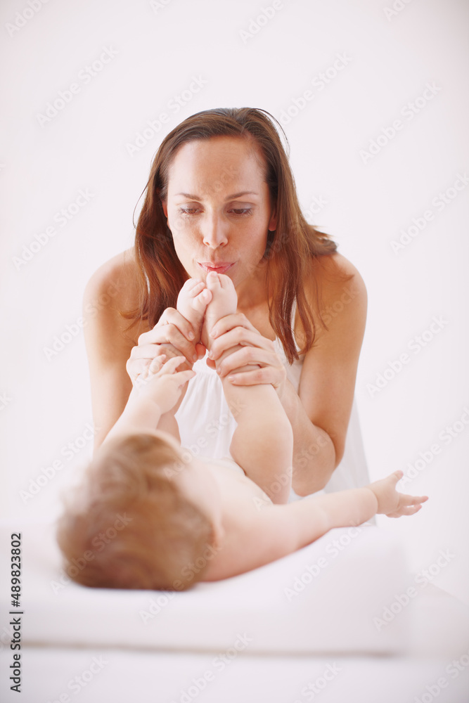 Let me kiss those cute clean toes. A young mother showing her baby daughter affection by kissing her