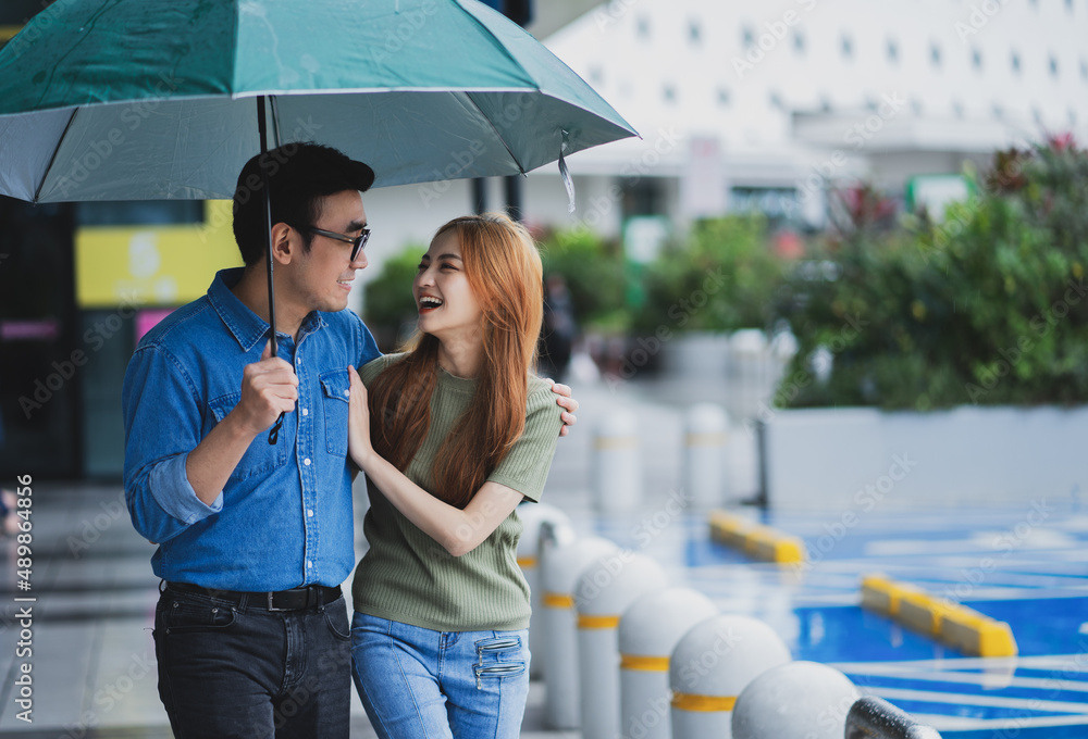 年轻的亚洲情侣在雨中行走