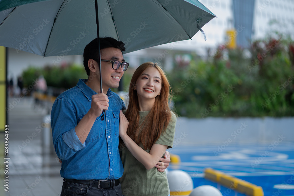 年轻的亚洲情侣在雨中行走