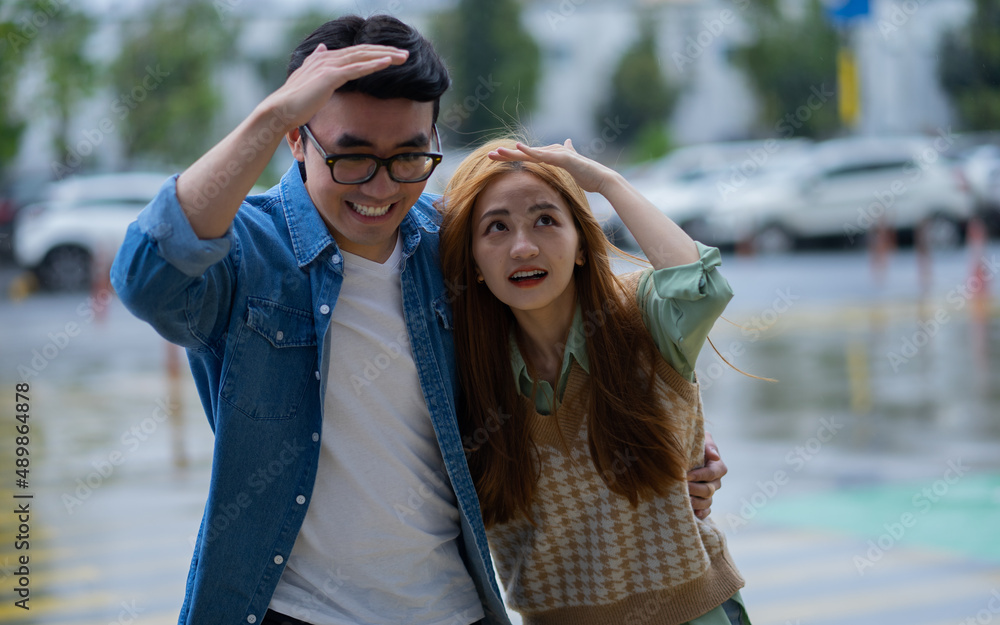 Young Asian couple walking in the rain