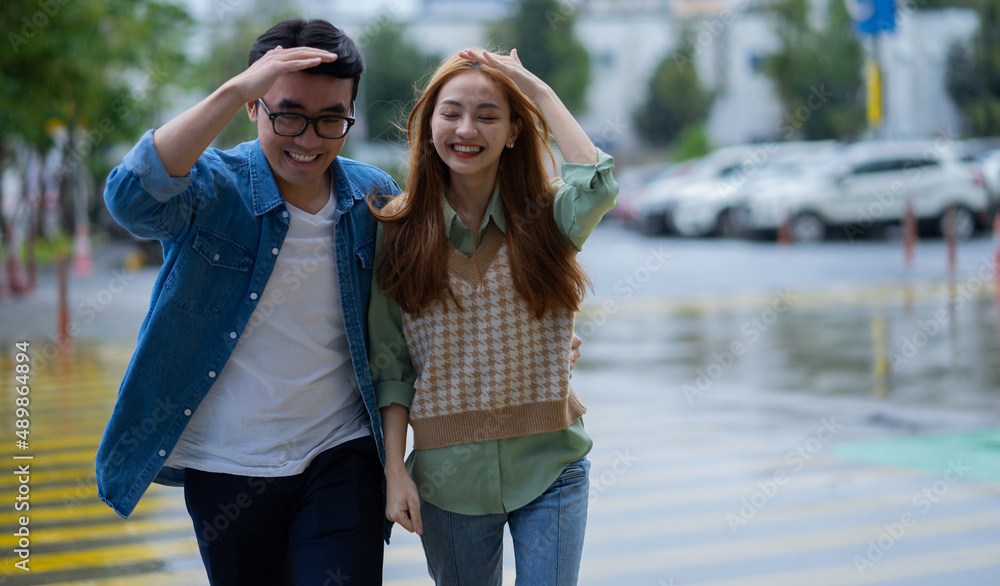 年轻的亚洲情侣在雨中行走