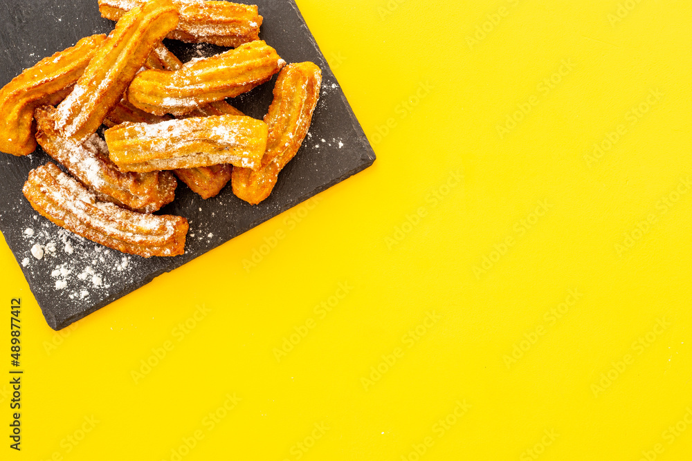 黑盘子里有糖粉的Churros。油腻的快餐糖果