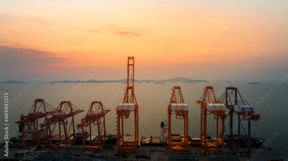 Crane load unload cargo container from truck to cargo ship at in the international bridge at sunset 