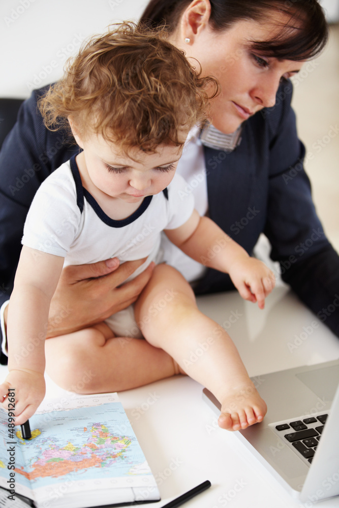 Juggling responsibilities. Working mother holding a baby while talking on the phone.