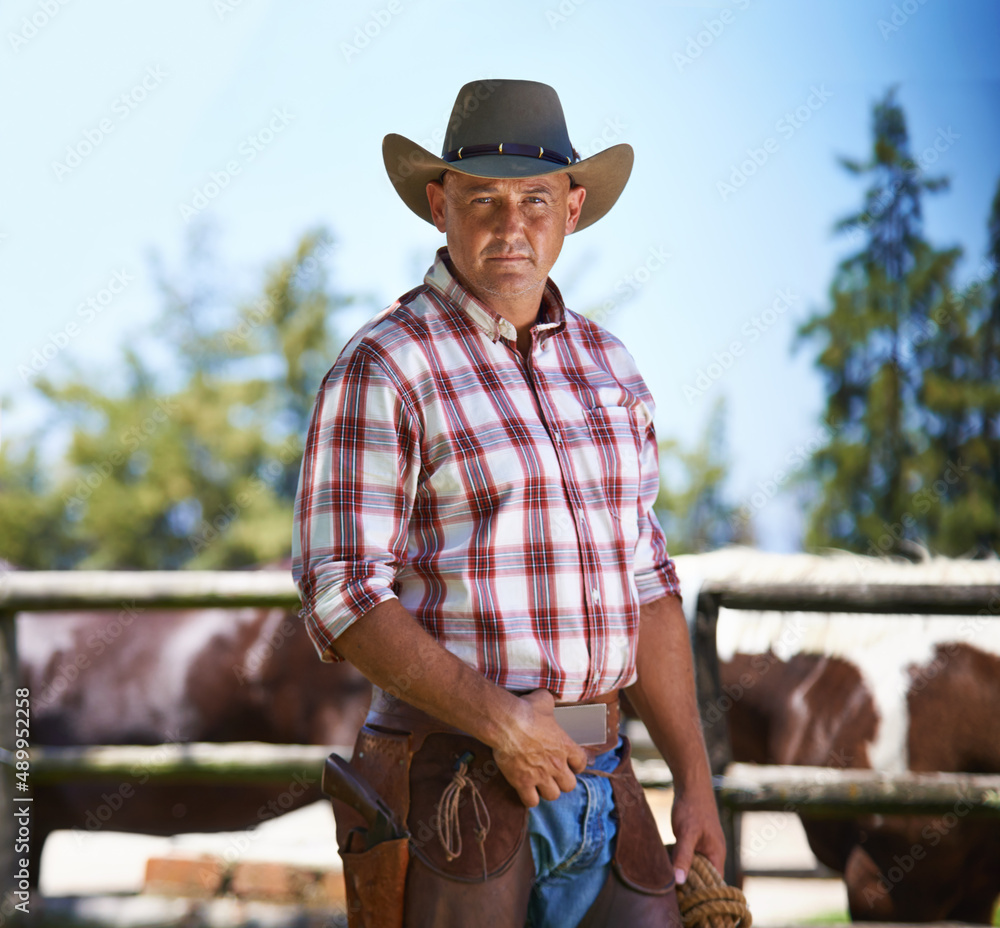 Hes the wrangler of beasts. A mature cowboy outdoors on his farm.