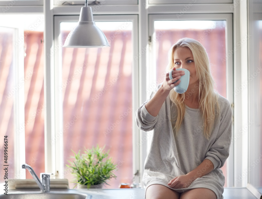 Relaxed in the morning. A pretty young woman enjoying a cup of coffee in the morning while sitting o