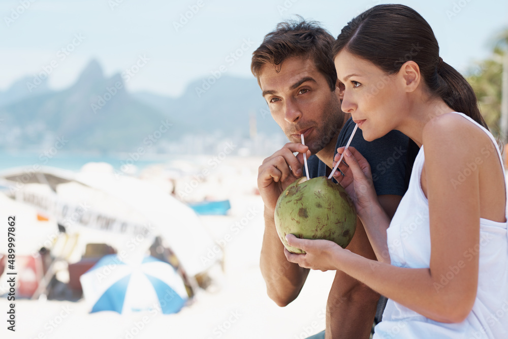 Enjoying something new with the person I love. Young couple enjoying a drink from a coconut while en