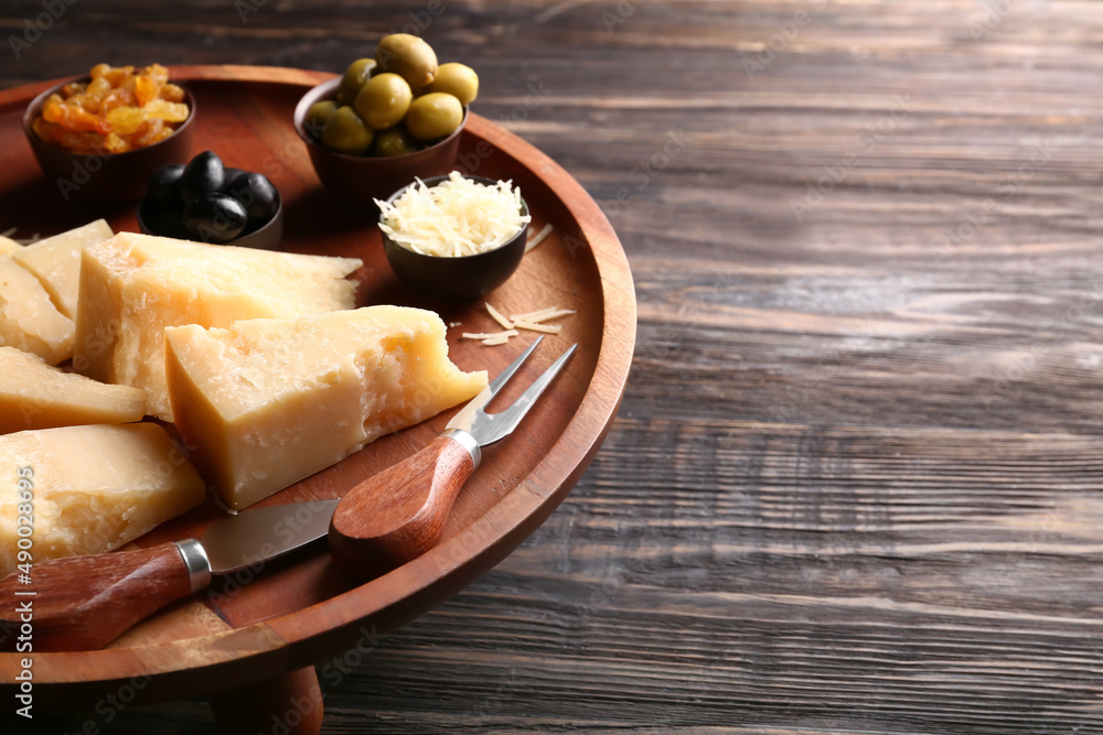 Stand with pieces of tasty Parmesan cheese on dark wooden background, closeup