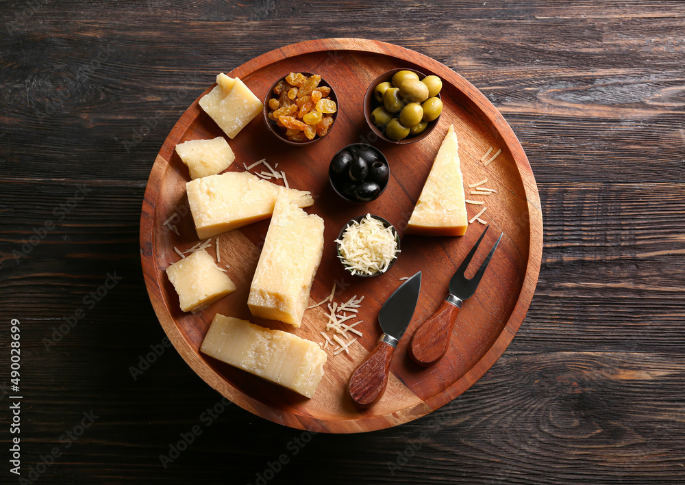 Stand with pieces of tasty Parmesan cheese on dark wooden background