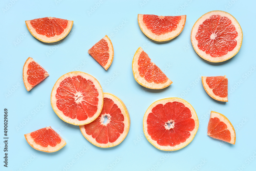 Slices of tasty ripe grapefruit on blue background