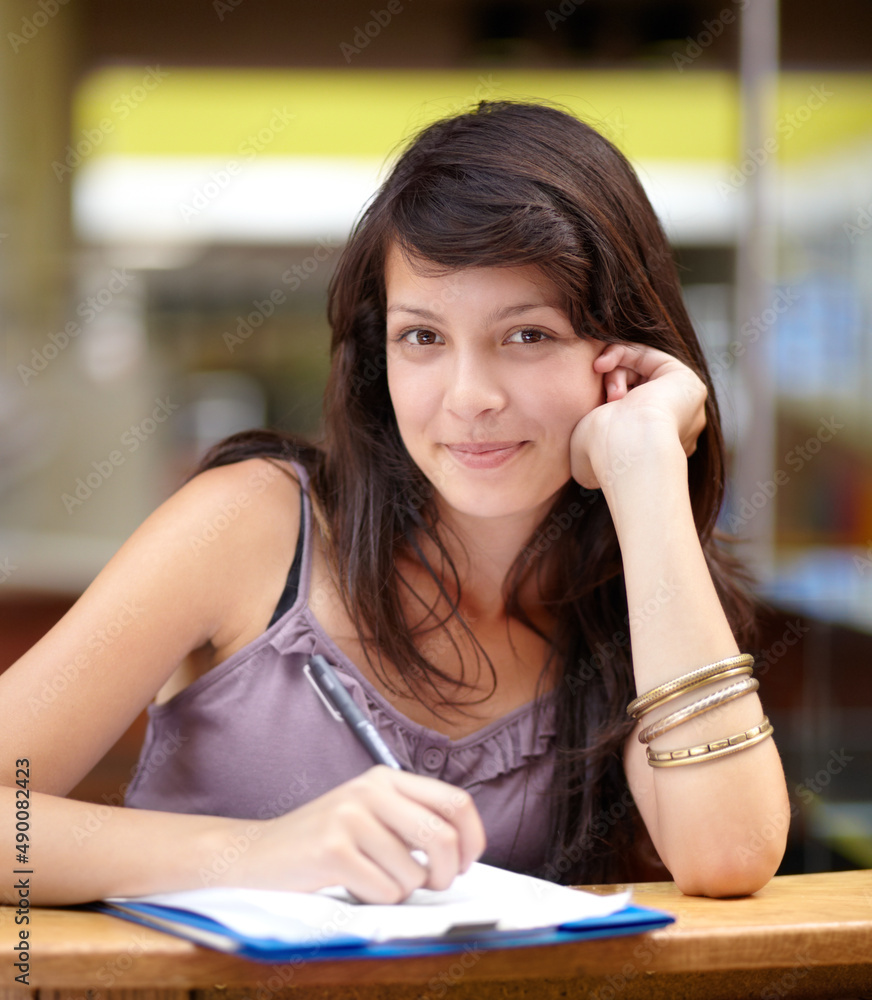 Shes a diligent student. A young attractive Indian woman taking notes in class.