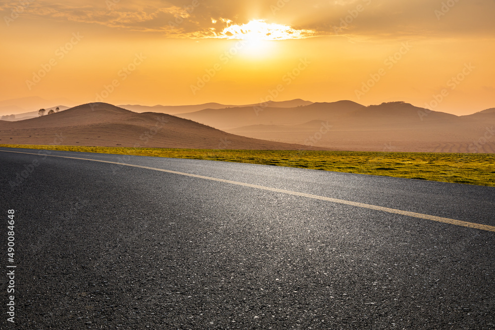 Empty asphalt road and foggy mountain nature scenery at sunrise