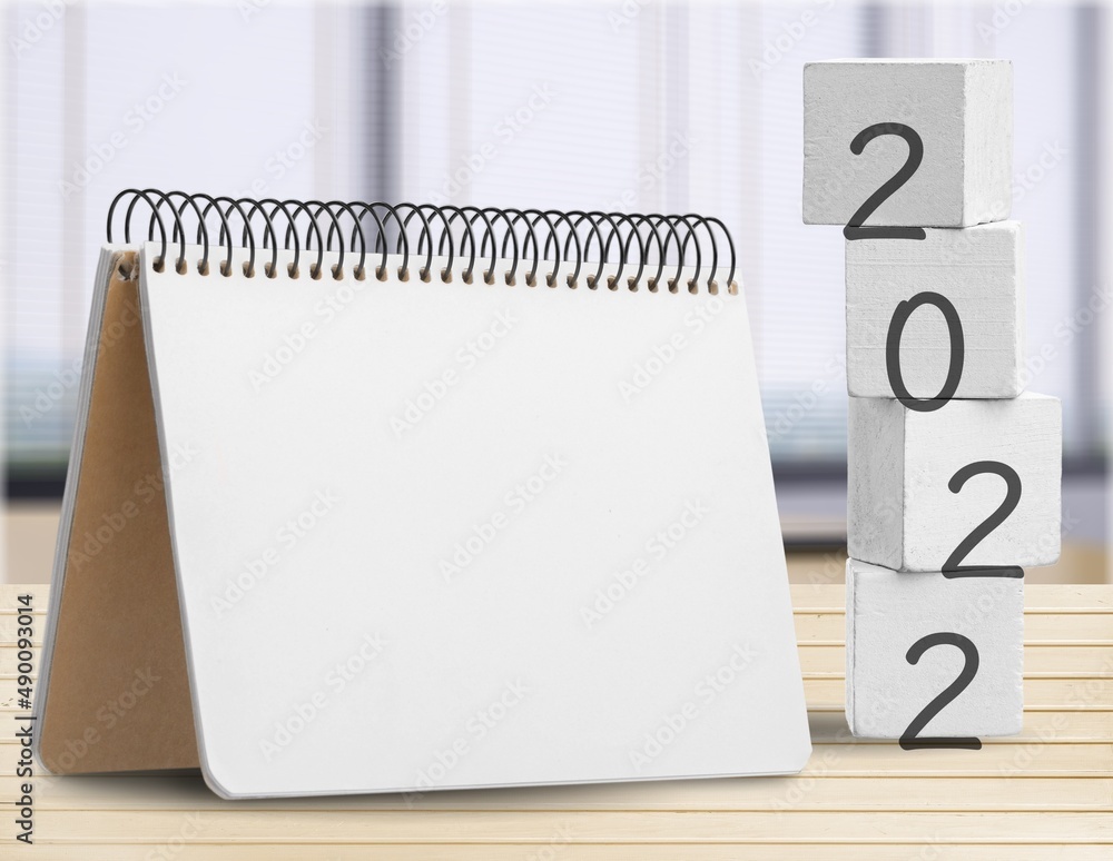 New year 2022 concept with cubes wooden on table background, notepad mockup calendar