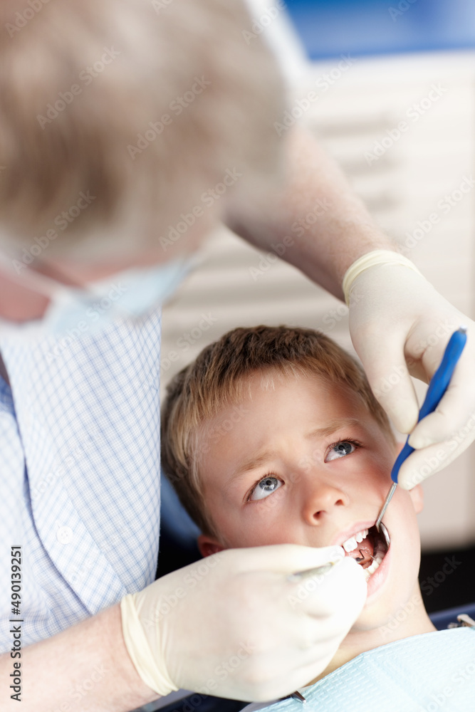 Doctor checking boys teeth. High angle view of doctor checking boys teeth in clinic.